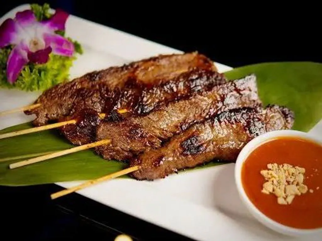 Grilled beef satay skewers served with peanut dipping sauce and orchid garnish at Green Papaya Thai Cuisine, a Thai Restaurant in Jacksonville